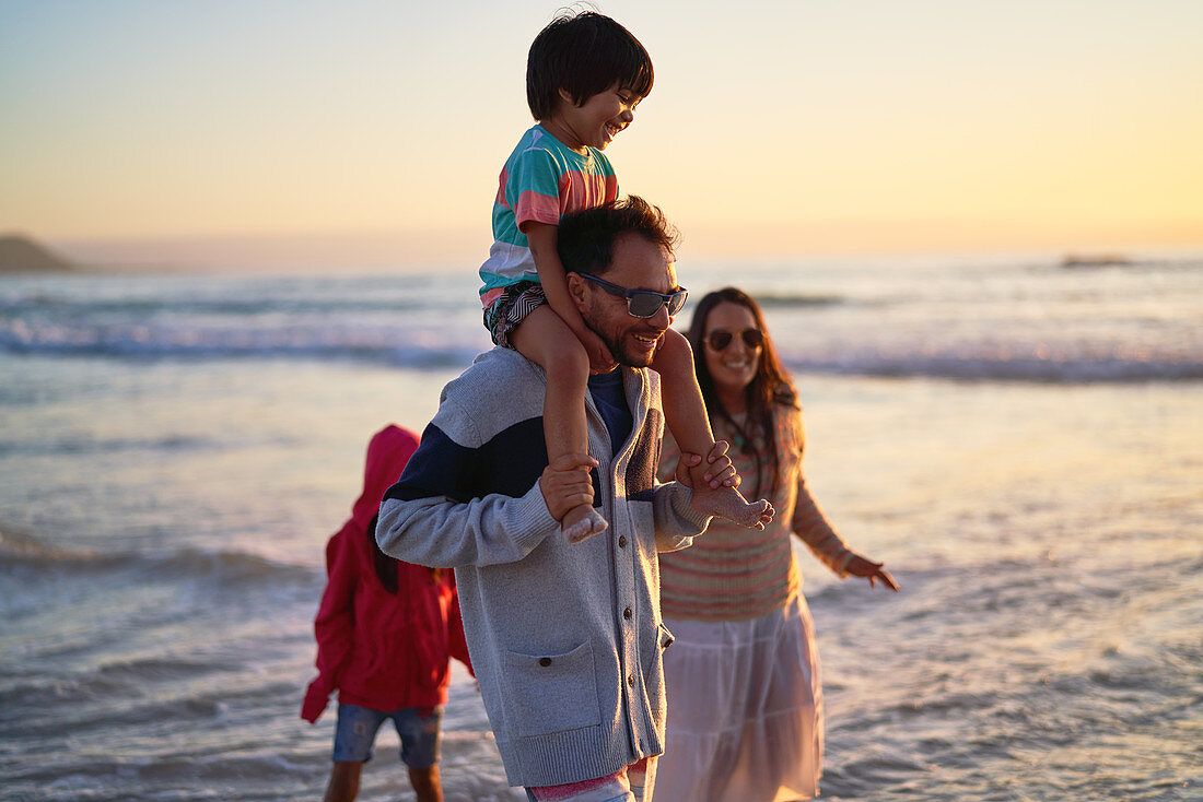 Happy family wading in ocean at sunset