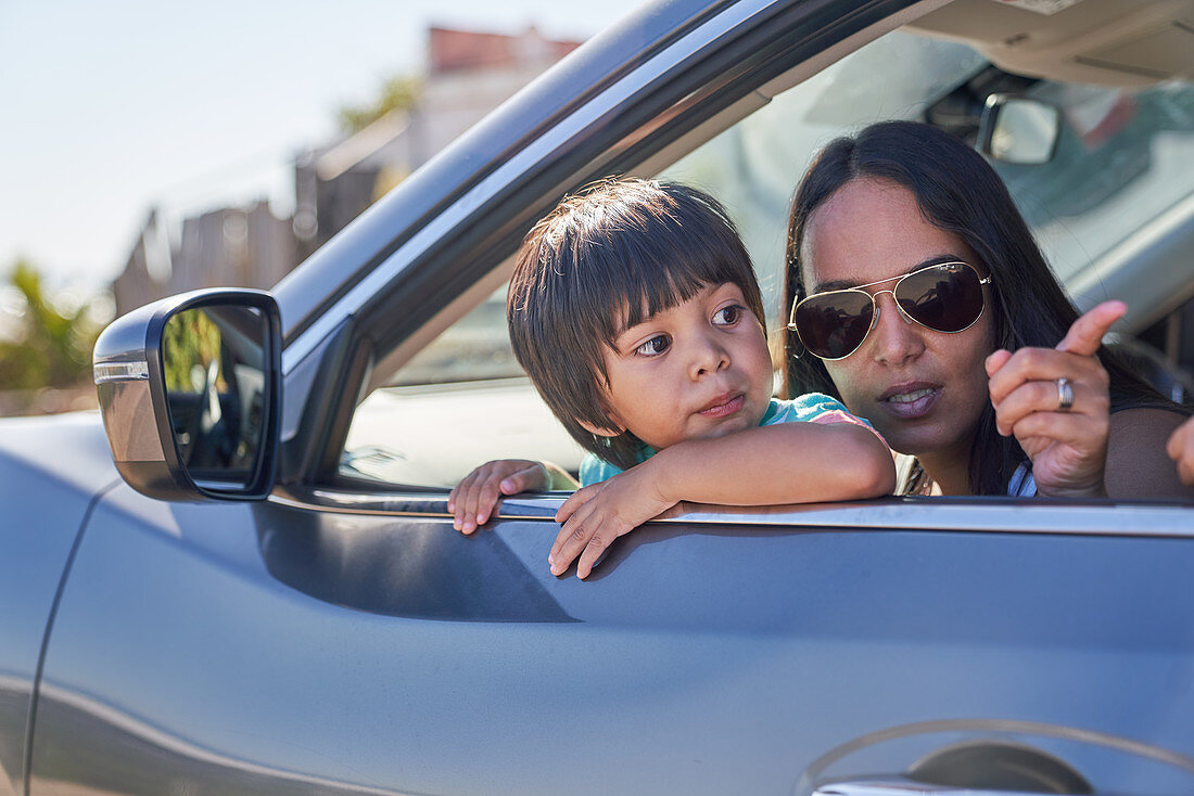 Mother and son looking out sunny car window