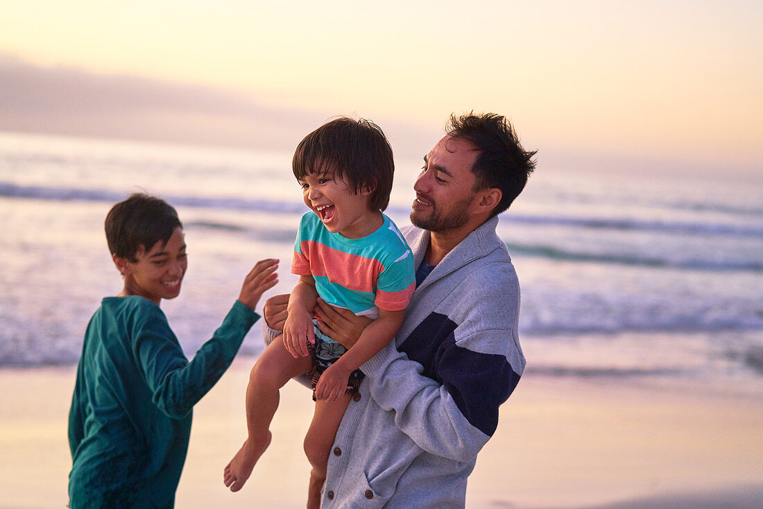Happy father and sons playing on ocean beach