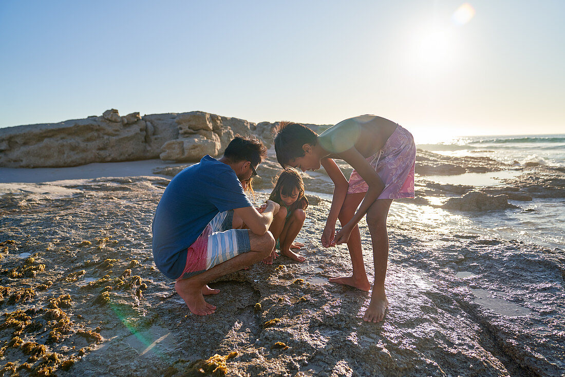 Family playing on rocks on sunny beach