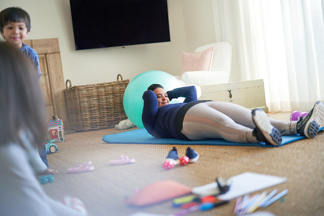 Mother exercising in living room with kids