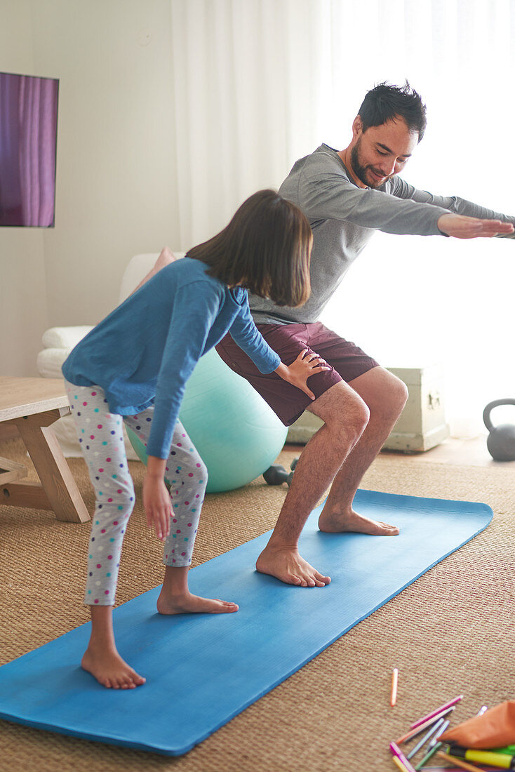 Father and daughter exercising on mat