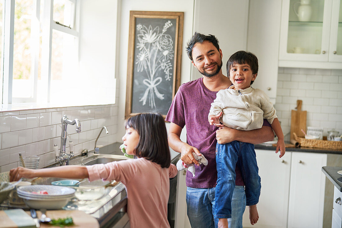 Father and kids doing dishes in kitchen