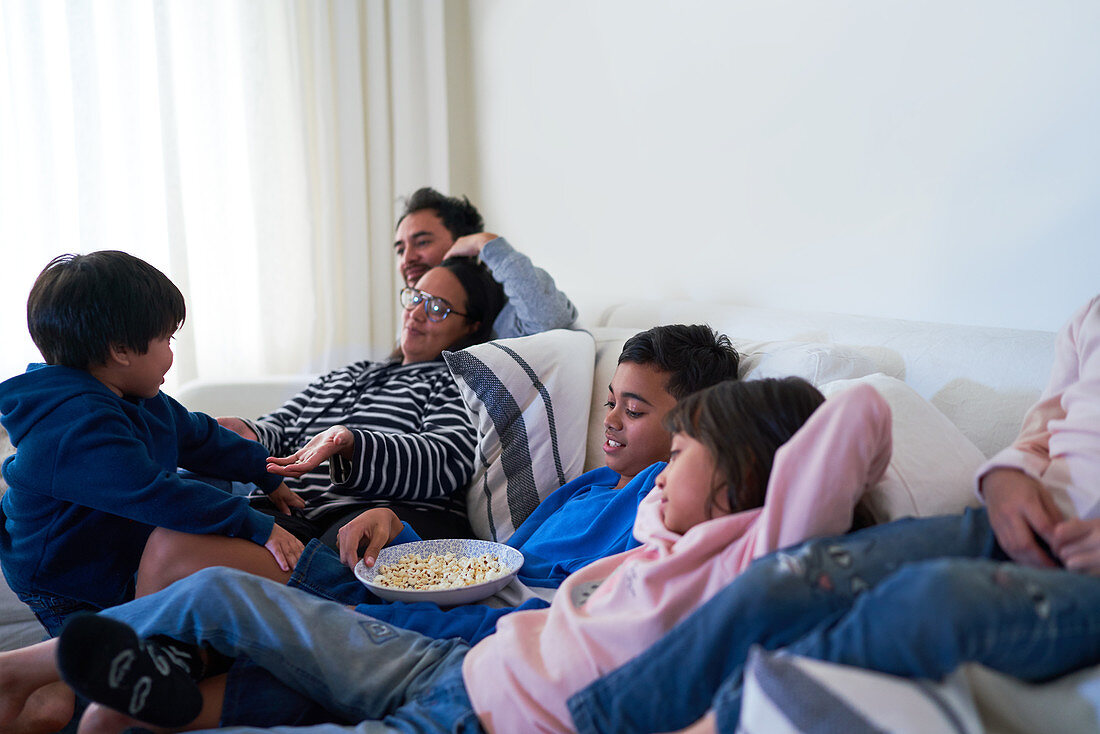 Family relaxing and eating popcorn on sofa