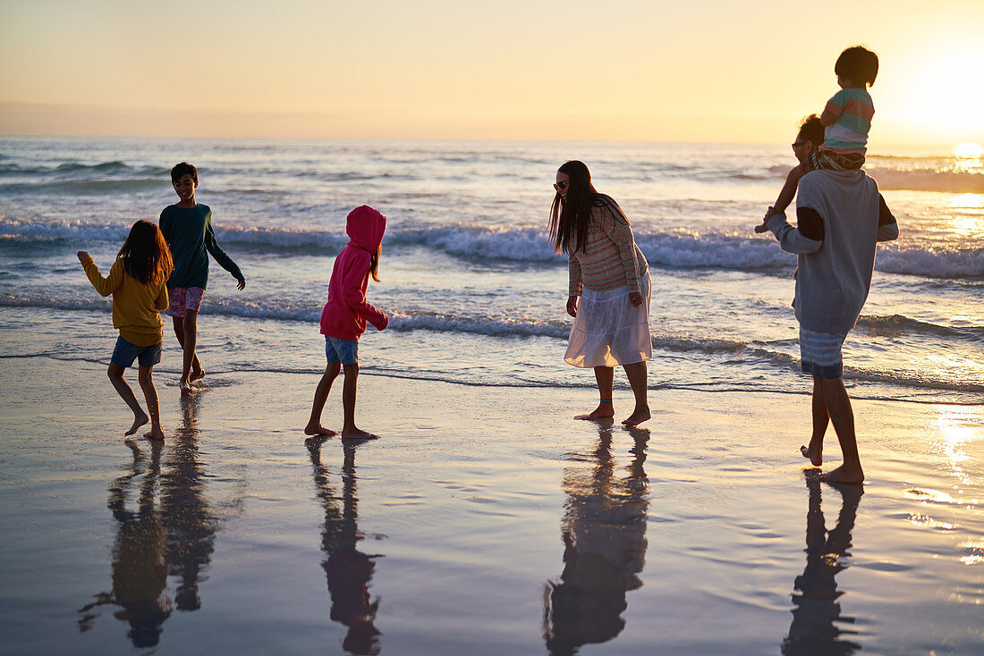 Family playing in ocean surf at sunset