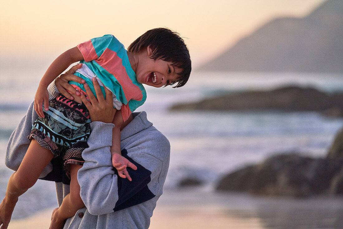 Happy father lifting laughing son on beach