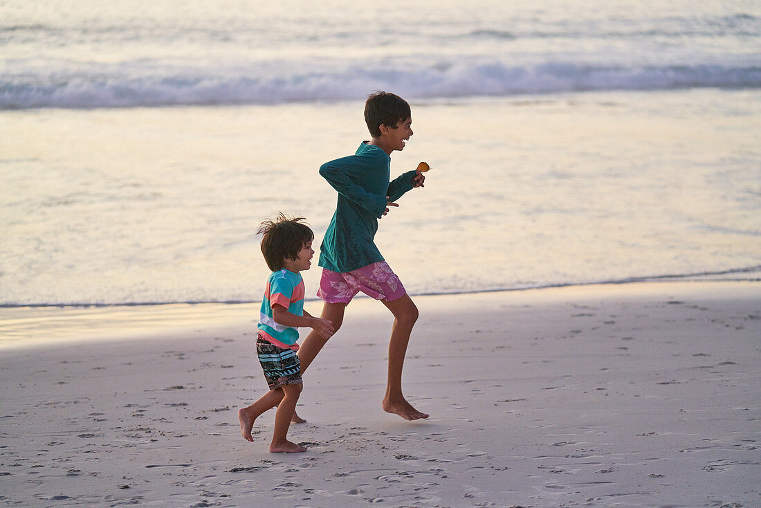 Happy brothers running on ocean beach