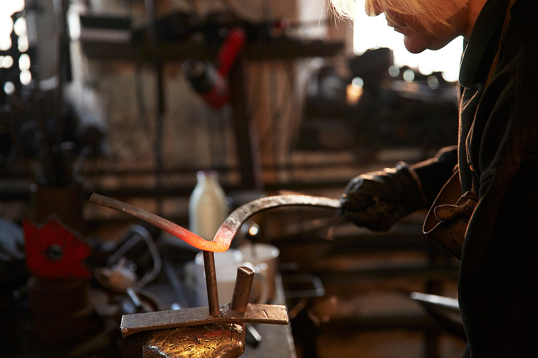 Female blacksmith shaping steel in workshop