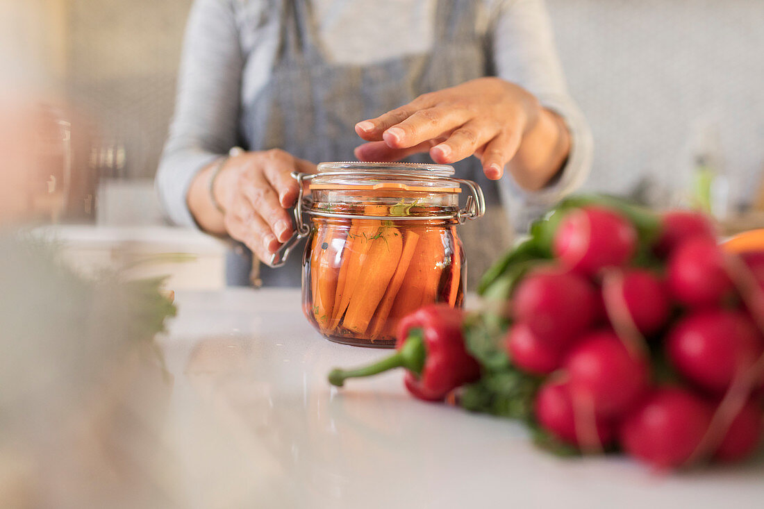 Woman preserving carrots in jar