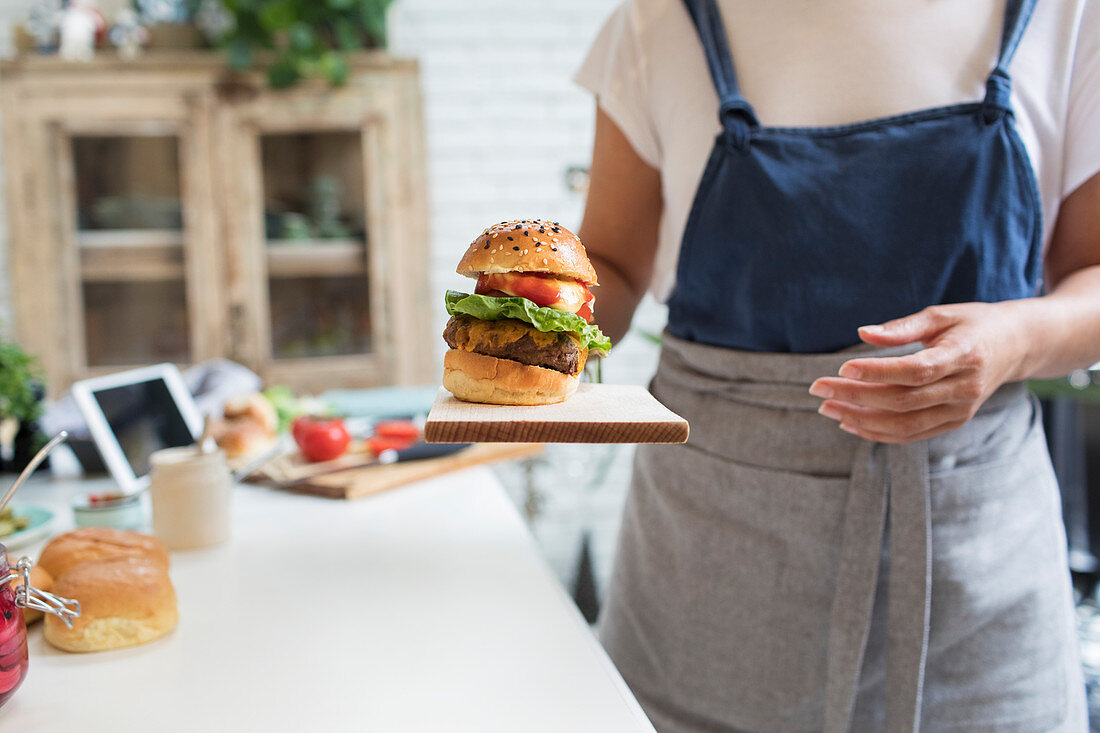 Woman serving hamburger on cutting board