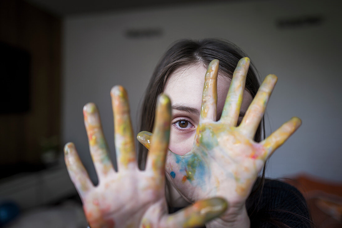 Close up girl with finger paint covering hands