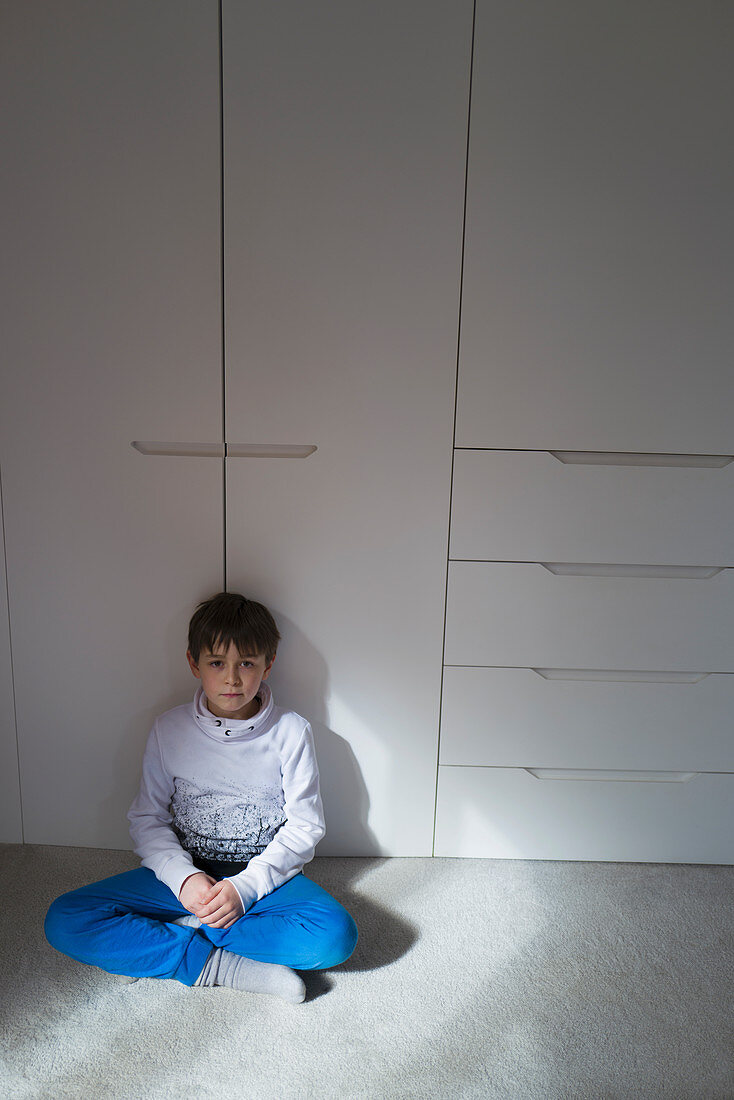 Portrait boy sitting at closet doors