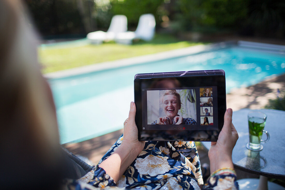 Woman video chatting with friends at poolside