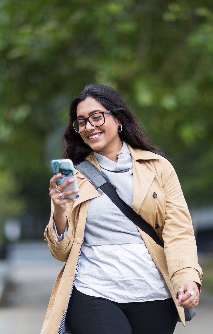 Smiling woman walking with smart phone