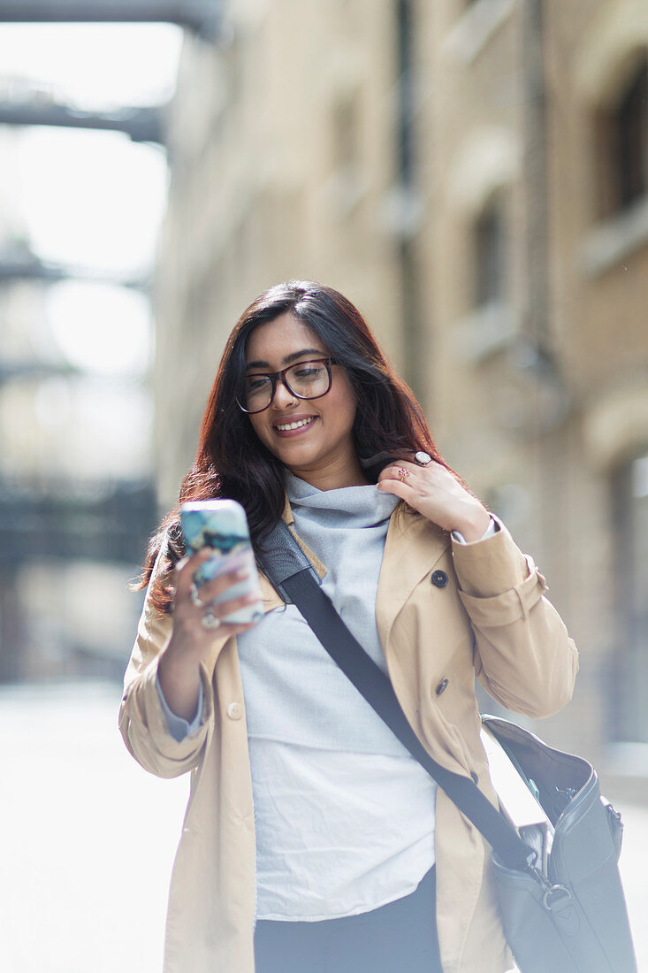 Smiling businesswoman using smart phone on street