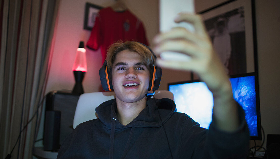 Smiling teenage boy taking selfie with smart phone