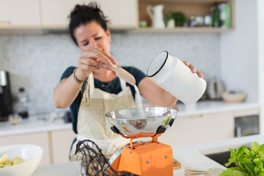 Woman measuring sugar at scale for baking