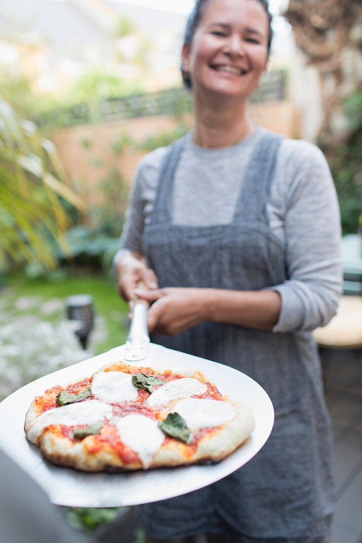 Woman cooking fresh homemade pizza outdoors