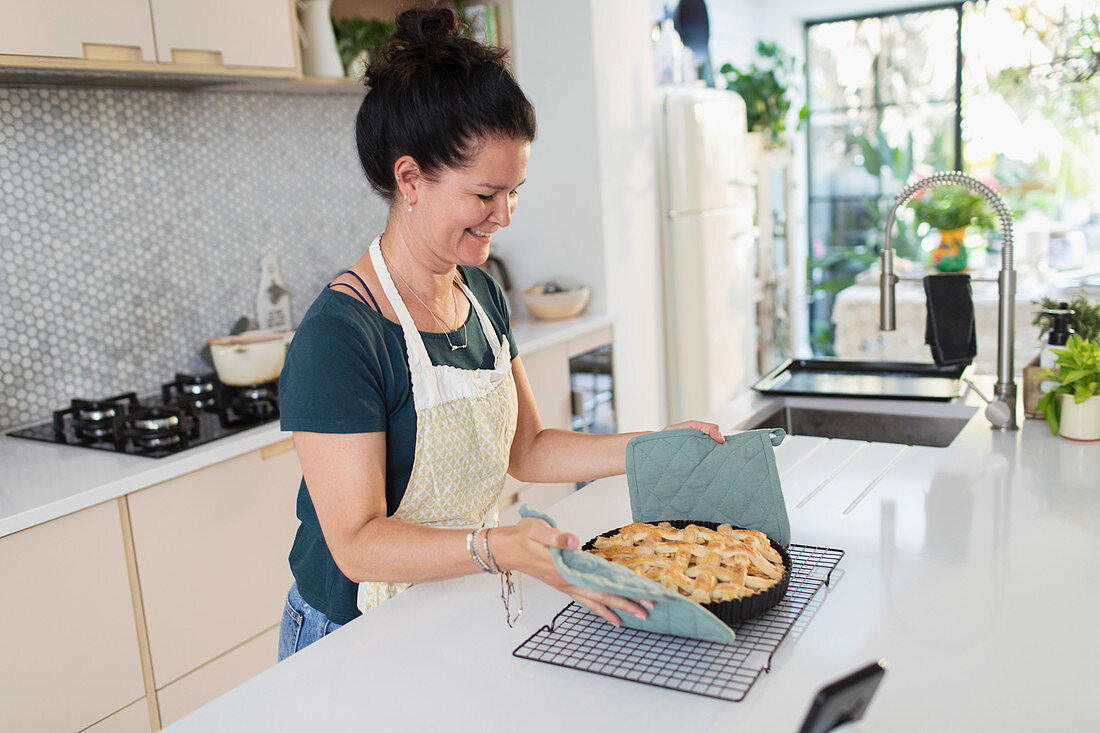 Woman placing hot apple pie on cooling rack
