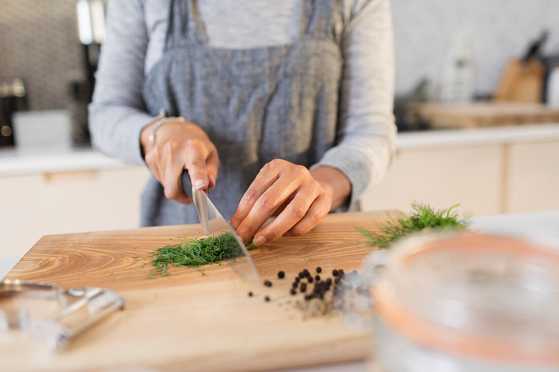 Woman slicing fresh herbs on cutting board