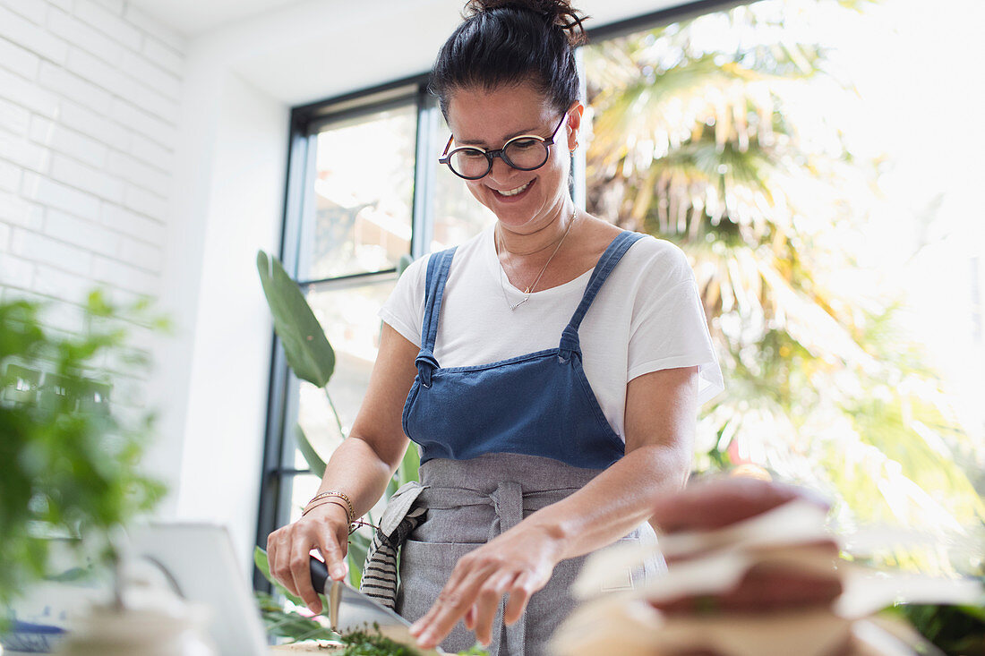 Smiling woman cutting fresh herbs