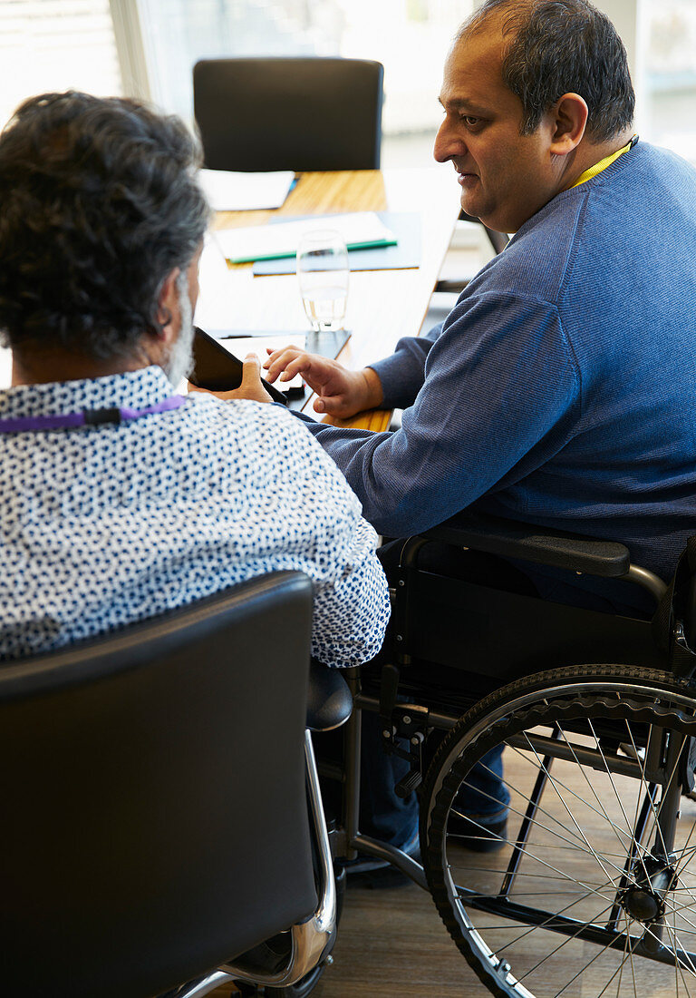 Businessman in wheelchair talking with colleague