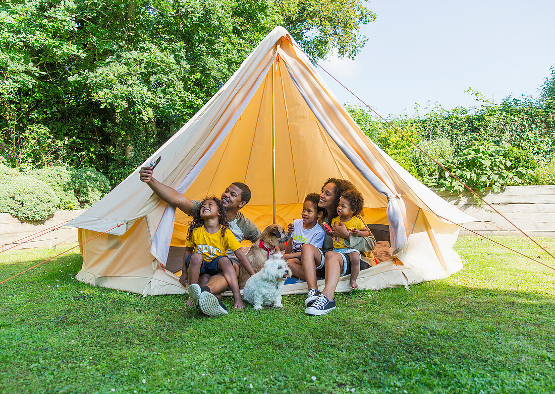 Happy family taking selfie in tent