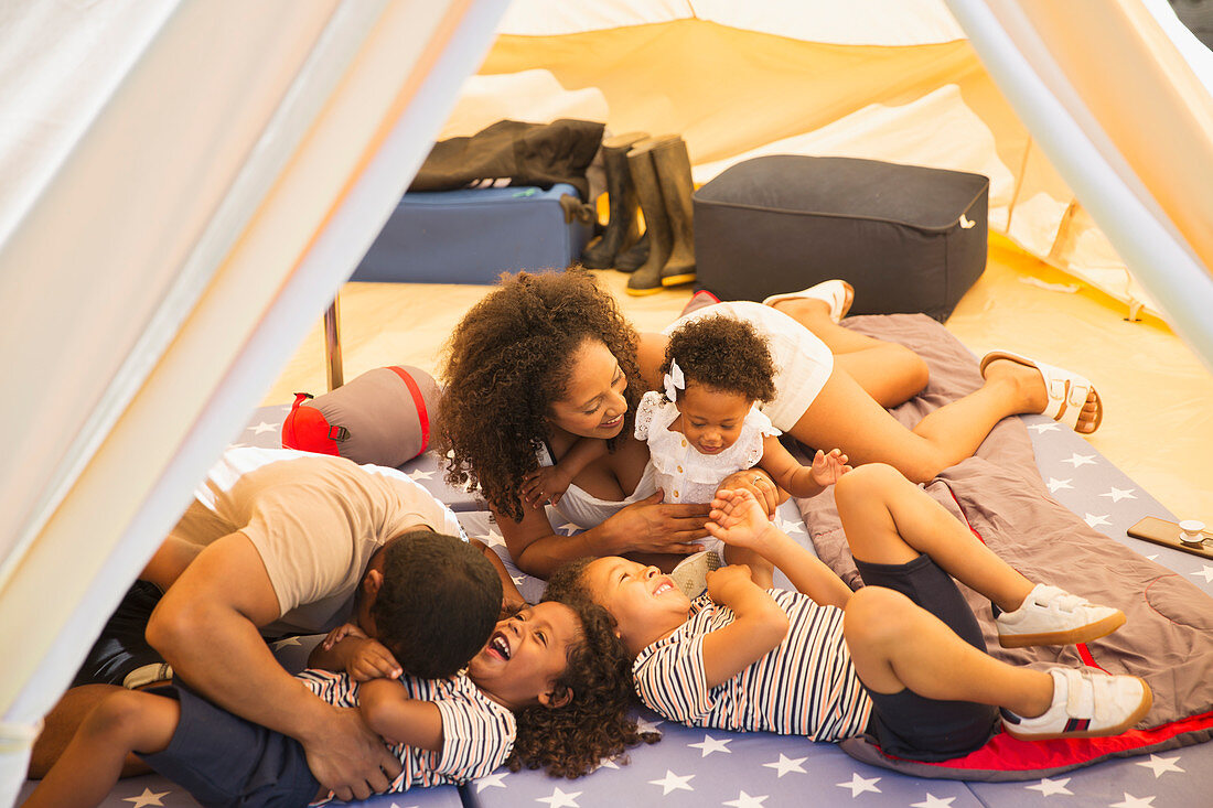 Playful family tickling and laughing inside tent