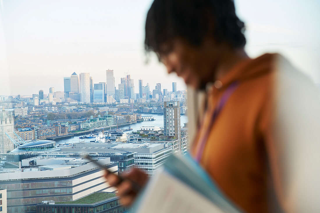 Businessman at highrise window, London, UK