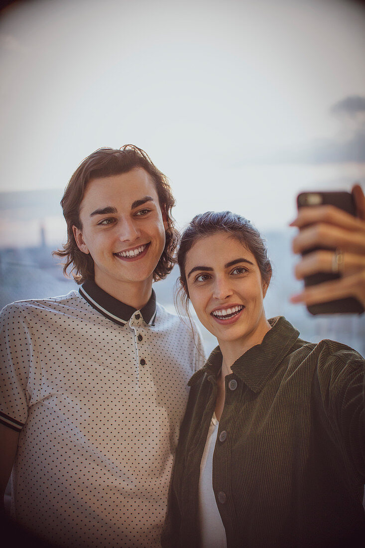 Couple taking selfie with camera phone at window