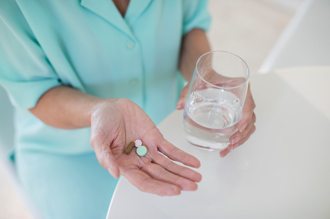 Senior woman taking vitamins with water