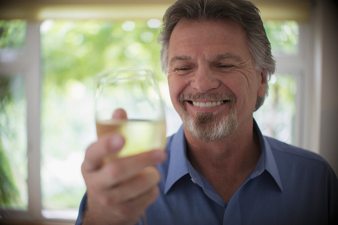 Close up smiling senior man drinking white wine