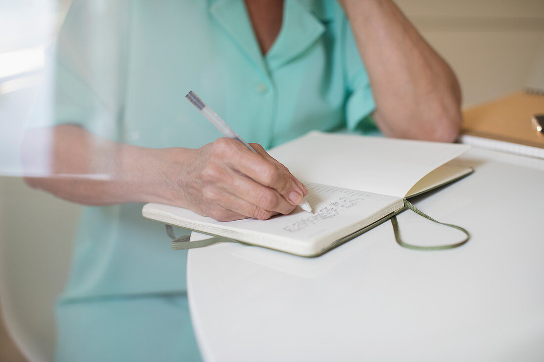 Close up senior woman writing in journal at table
