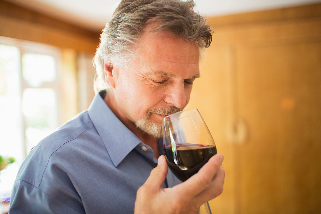 Close up serene man smelling and tasting red wine