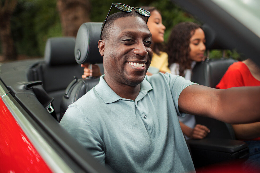 Happy man driving in convertible with family