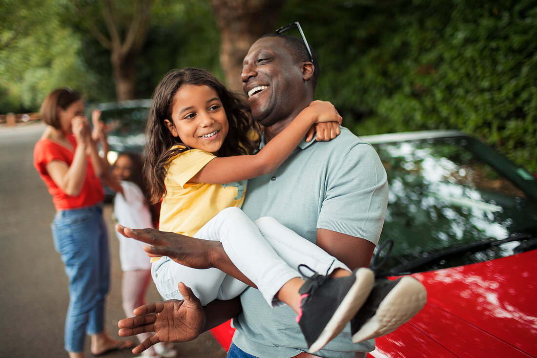 Happy father holding daughter outside convertible