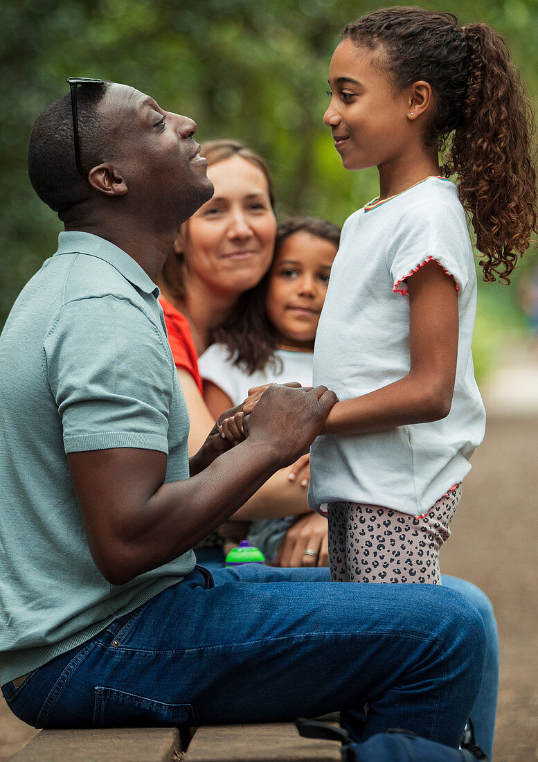 Happy family talking on park bench