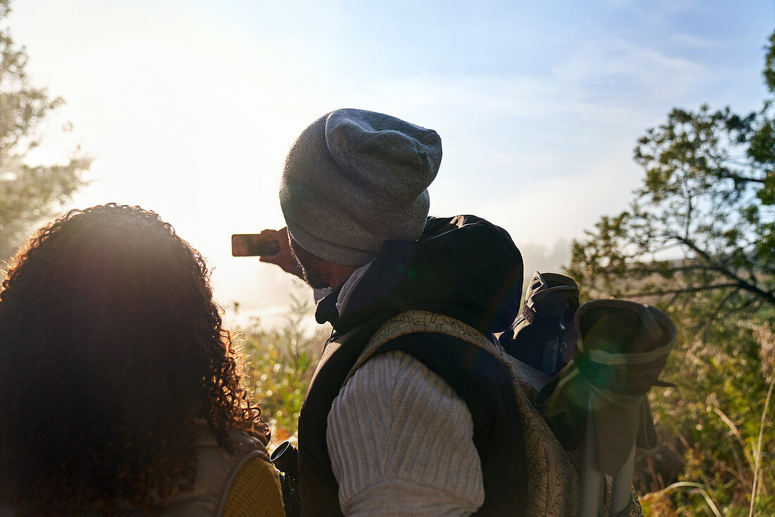 Couple hiking and using camera phone in woods