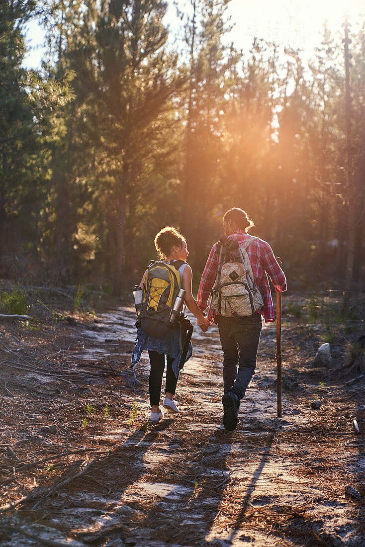 Young couple with backpacks hiking in sunny woods