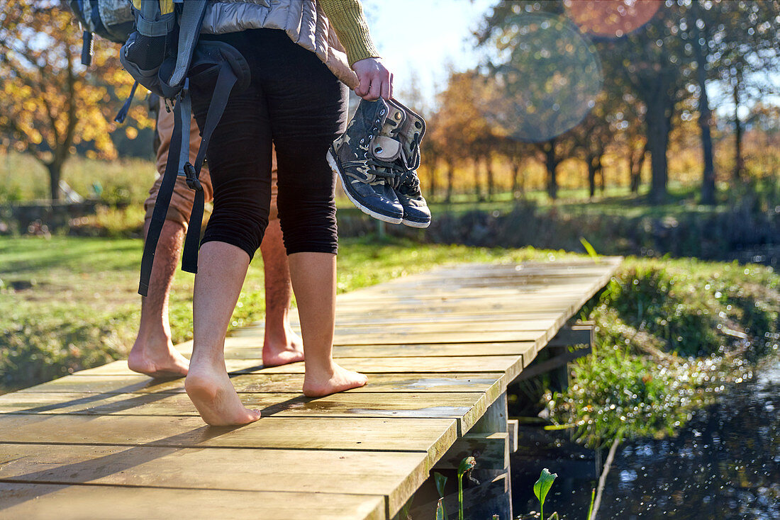 Barefoot young couple walking on sunny autumn dock