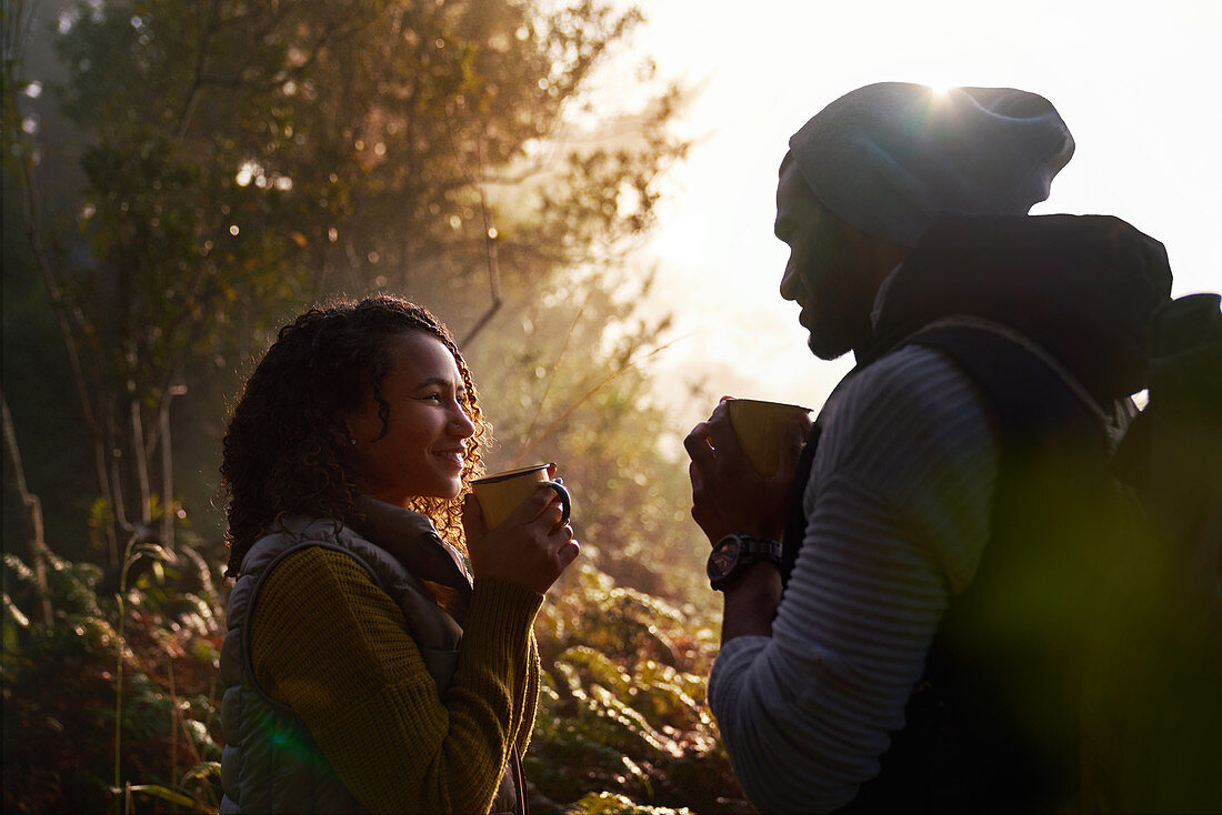 Happy hiking couple drinking coffee in sunny woods