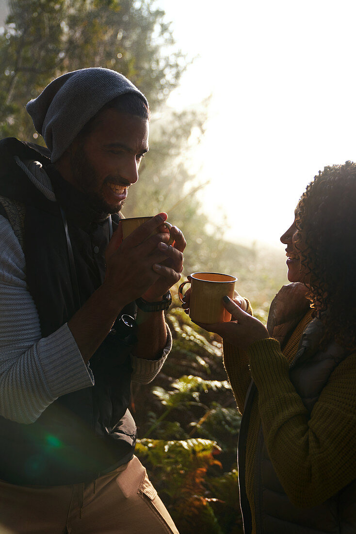 Happy hiker couple drinking coffee in sunny woods