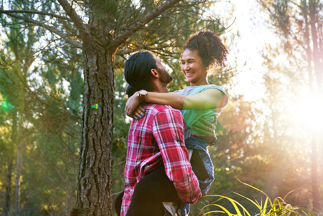 Affectionate man holding happy girlfriend in woods