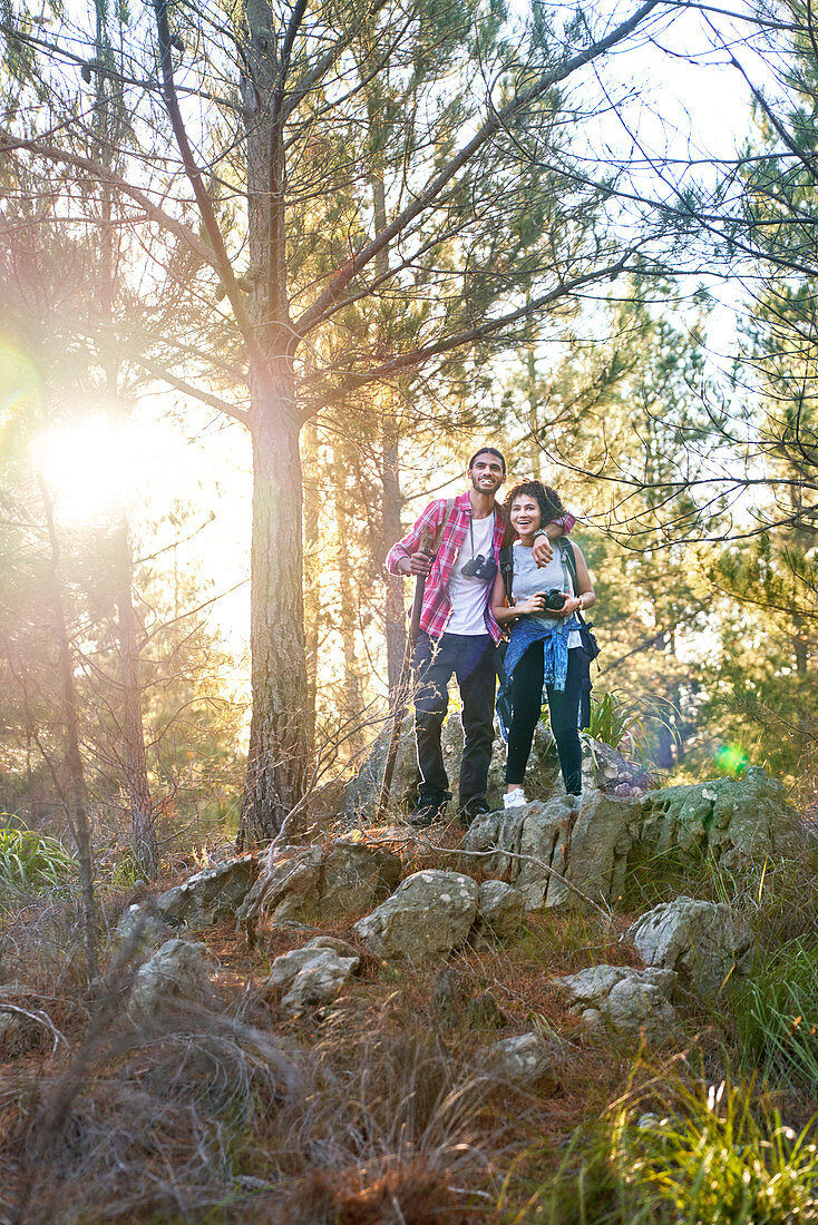 Happy young couple hiking in sunny woods