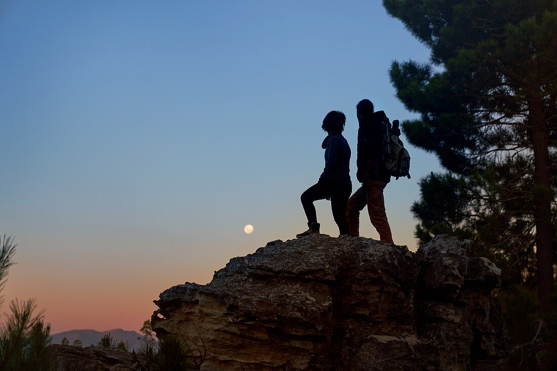 Hiker couple enjoying view of moon at dusk