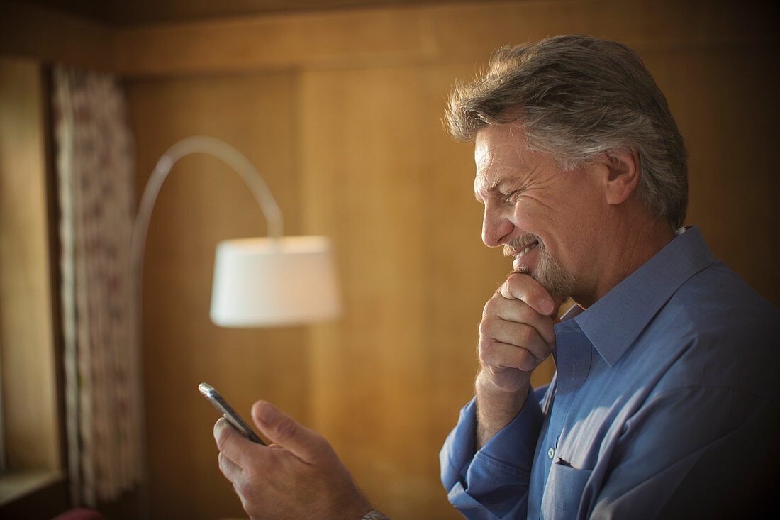 Smiling senior man using smart phone at home