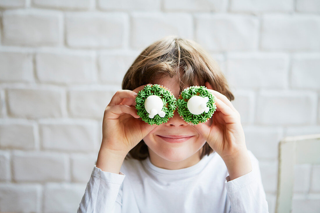 Boy using bunny cupcakes as glasses