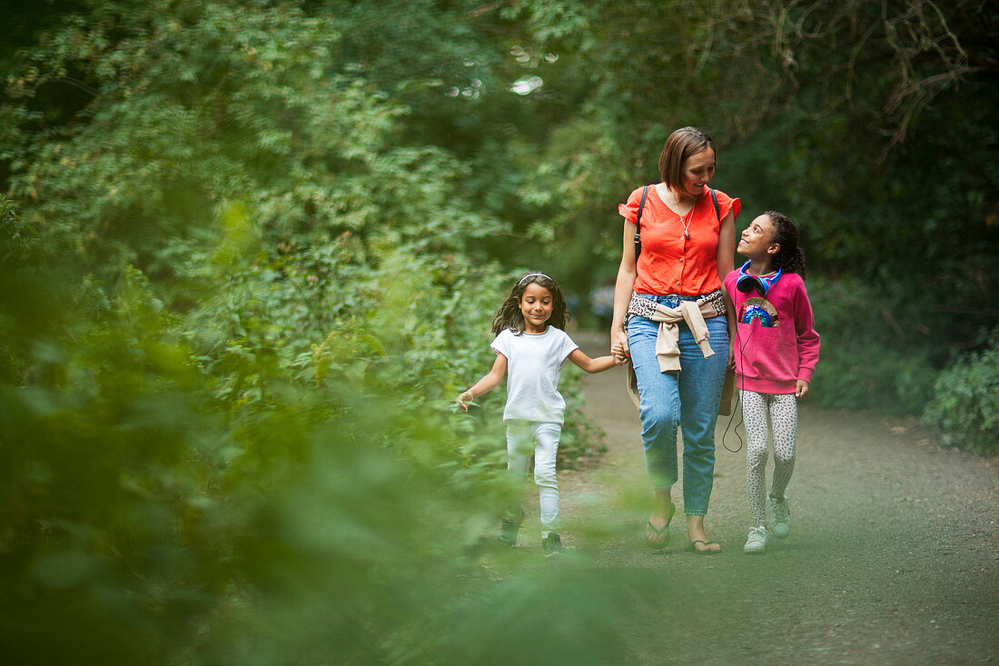 Mother and daughters walking on path in woods