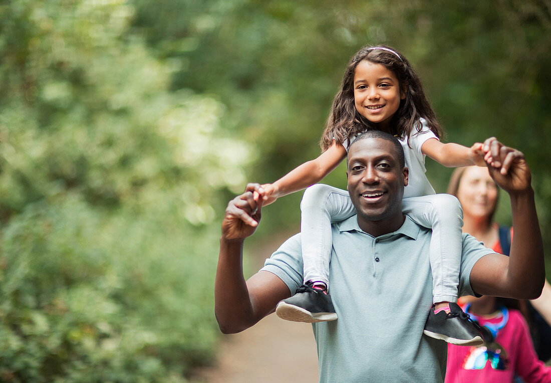 Father carrying daughter on shoulders on path