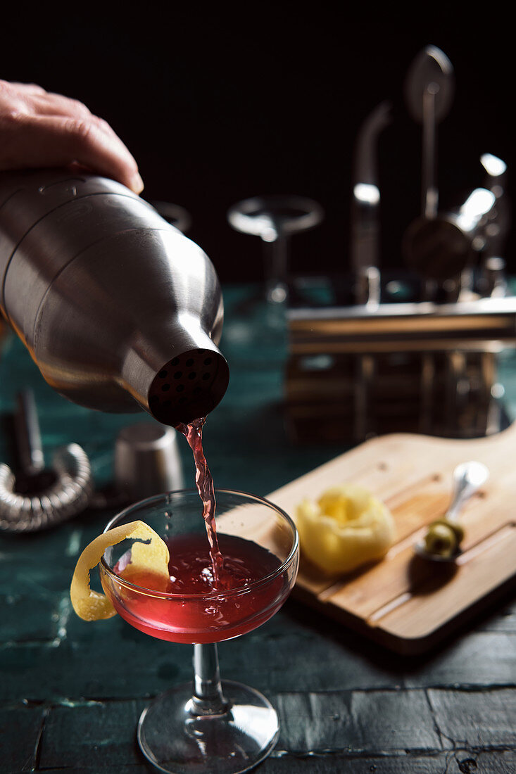 Barkeeper giesst Cocktail aus Shaker in Glas